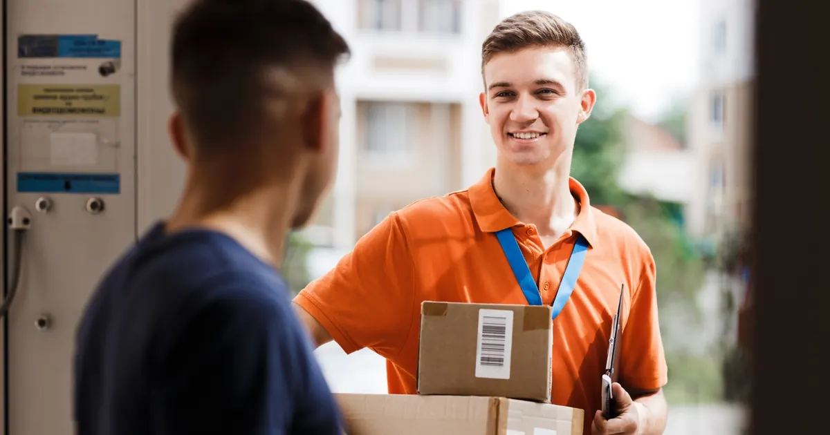 Zusteller übergibt einem Kunden ein Paket vor der Haustür.